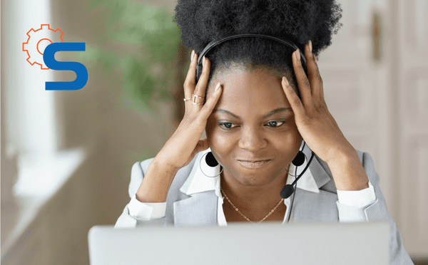 Mulher negra em frente ao computador utilizando fone de atendimento com expressão facial remetendo a preocupação com a queda de pedidos dos clientes.